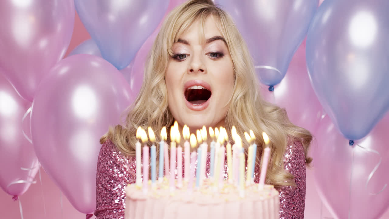 hermosa mujer joven soplando velas celebrando su cumpleaños fondo de globo rosa y azul - dragón épico rojo