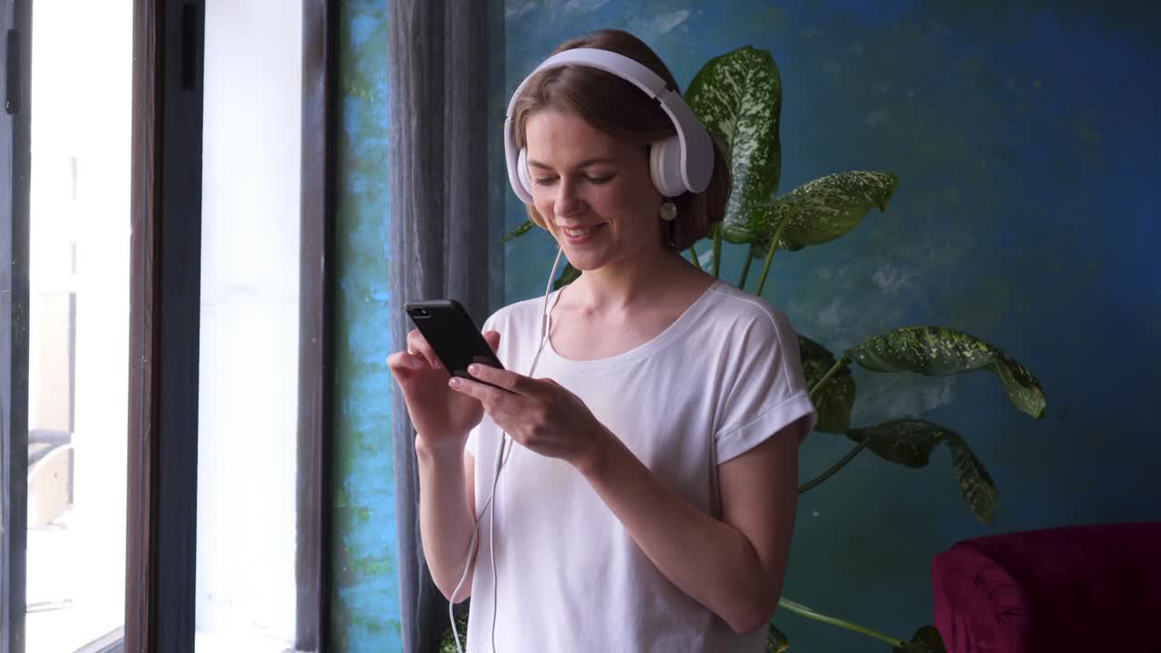 una chica bonita eligiendo una canción en su teléfono.