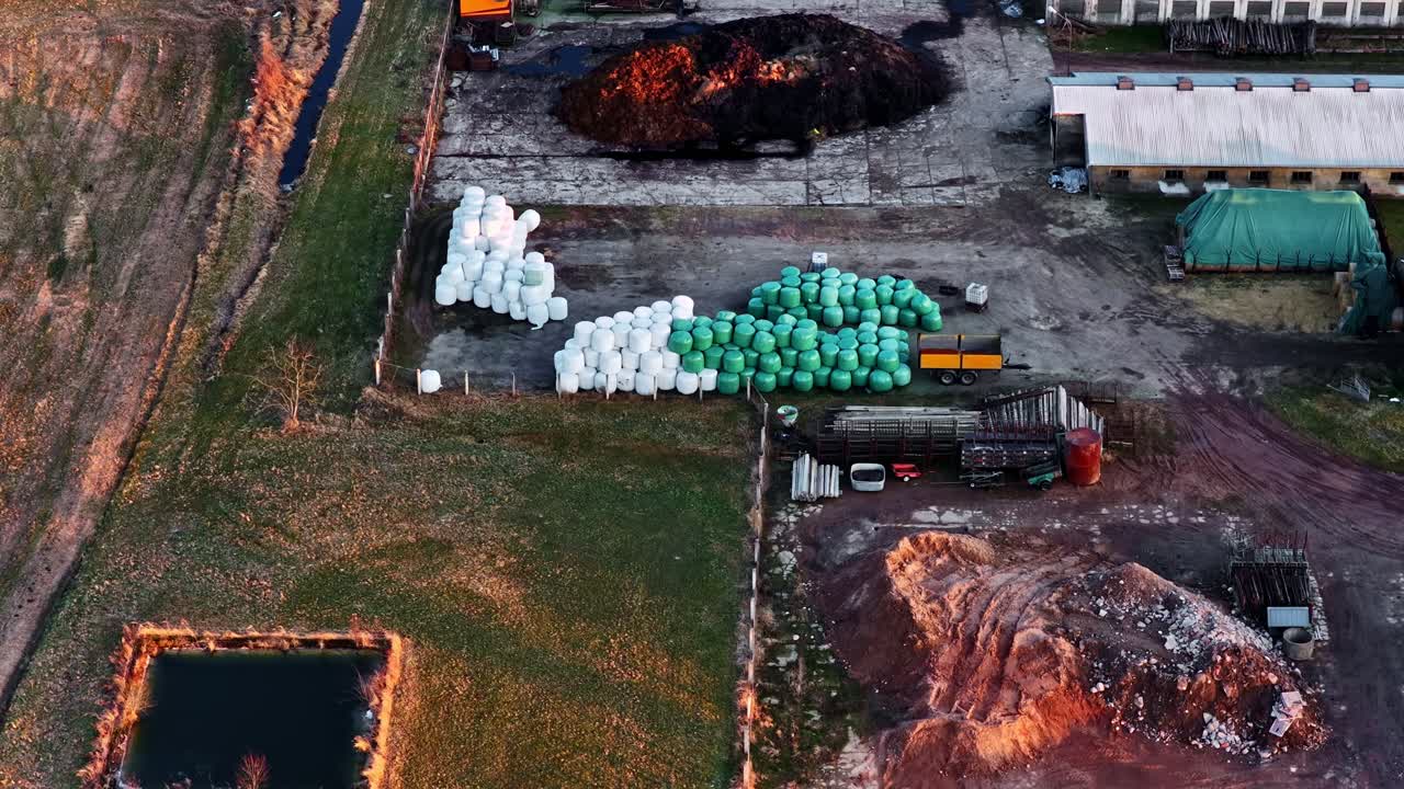 Farm buildings with feed production and large bales storage in aerial view during golden hour