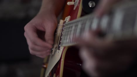 man goes from strumming chords to picking individual notes on a les paul style guitar - close up side shot of his strumming hand