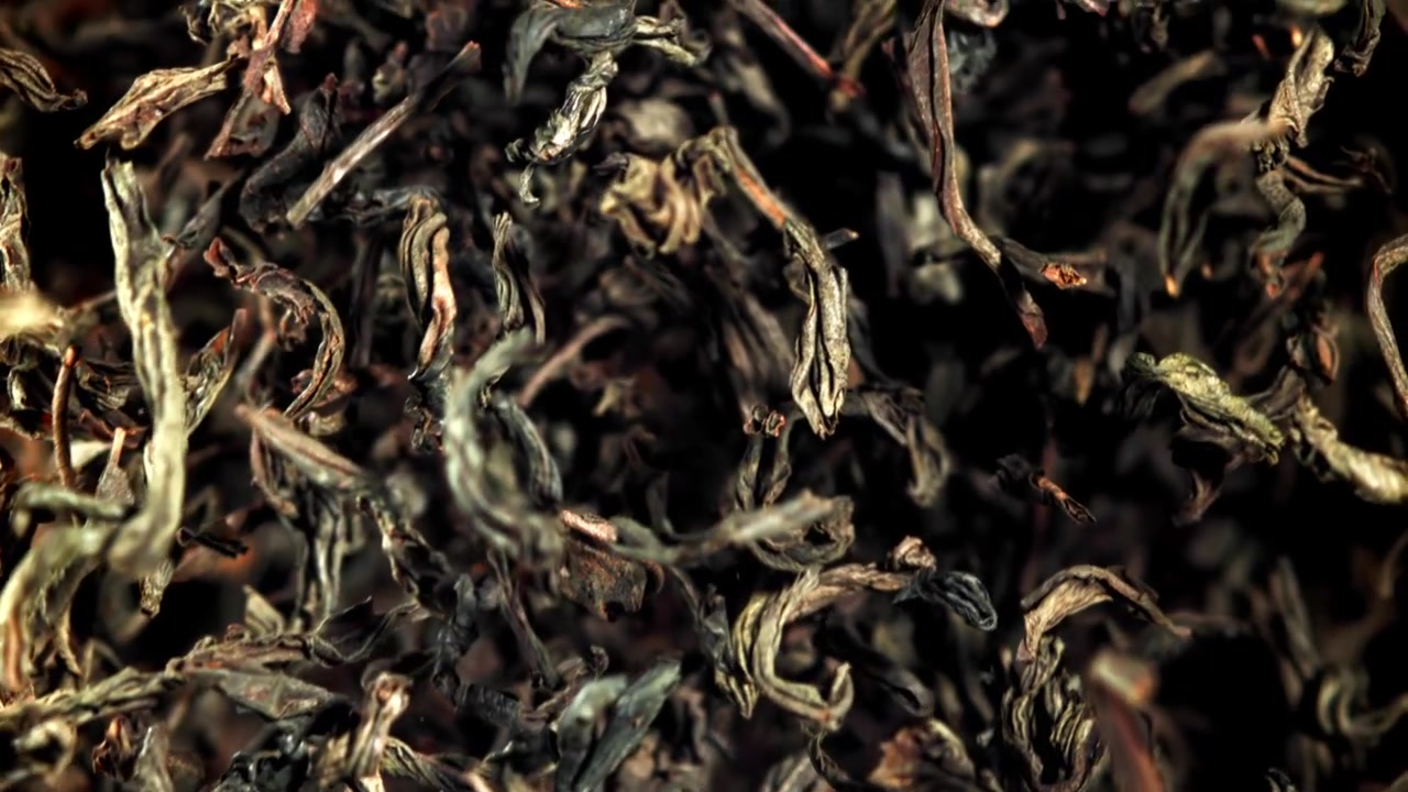 Dried Tea Leaves Falling in Slow Motion on Black Background