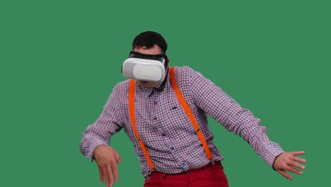 portrait of a dancing man with a virtual reality headset or 3d glasses on his head. a man with glasses, a shirt with orange suspenders in the studio on a green screen. slow motion. close up