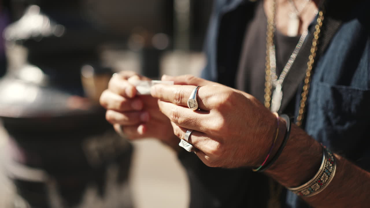 Man rolling cigarette with stylish accessories