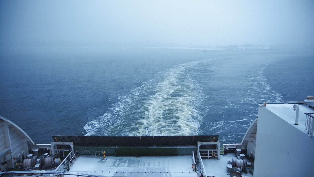 View from the stern of a ferry creating a wake in misty winter waters