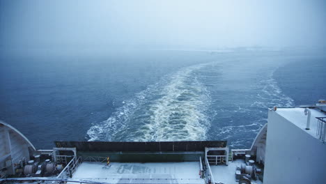view from the stern of a ferry creating a wake in misty winter waters