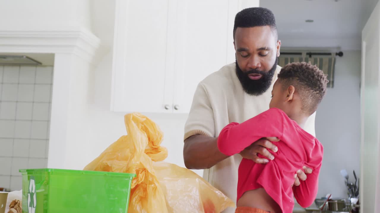 행복한 아프리카계 미국인 아버지와 아들이 천천히 부 ⁇ 에서 쓰레기를 분류하고 있습니다.