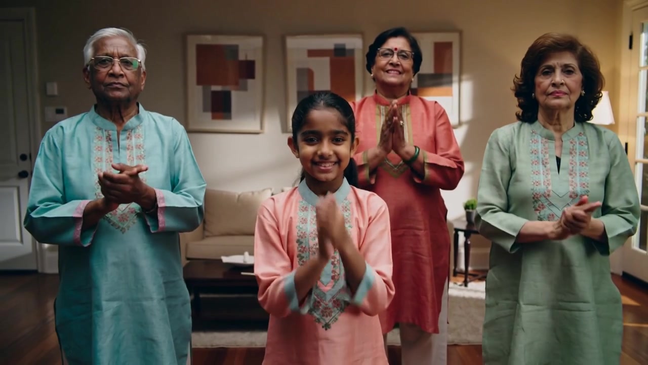 Smiling girl leading clapping in living room for celebration, family echoing, embroidered kurtas