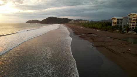 Strand-Von-Costa-Rica-Bei-Sonnenuntergang-Mit-Wellen-Und-Hotels-Direkt-Am-Meer