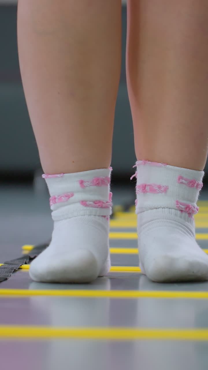 안정성 및 조율을 위해 민한 사다리에 뛰어드는 사람의 다리 시각과 배경의 소파의 부분적인 시각, 피트니스 드릴은 민함에 초점을 맞추고 체육관 환경에서 체력 훈련