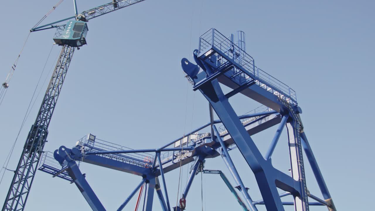 Beautiful low angle pan of a crane near a pre-piling template being constructed. The piling template will be used to place offshore wind turbines in deep water