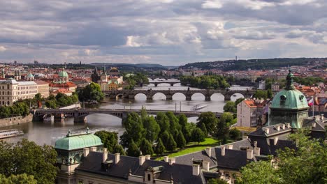 Cloudy-afternoon-timelapse-of-the-Vltava-river-in-Prague,-Czech-Republic-from-Letna-park-as-clouds-and-boats-pass-by-on-a-summer-day-with-Strakovska-akademie-and-Charles-Bridge-in-frame