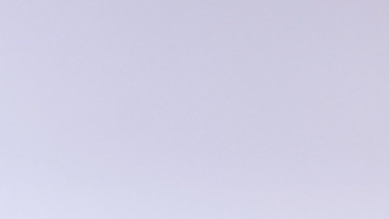 A pink tennis ball appears suspended in mid-air against a clear, light background.