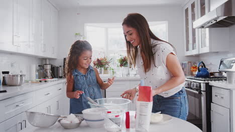 Young-girl-putting-cake-mix-on-her-mum’s-nose-while-they-bake-together-in-the-kitchen,-close-up