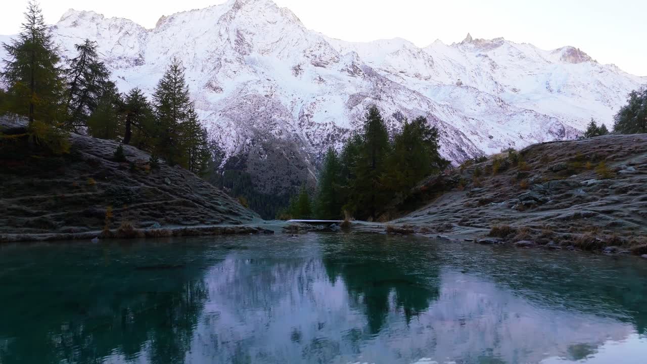 Riflesso mozzafiato di montagne innevate in un lago alpino cristallino.