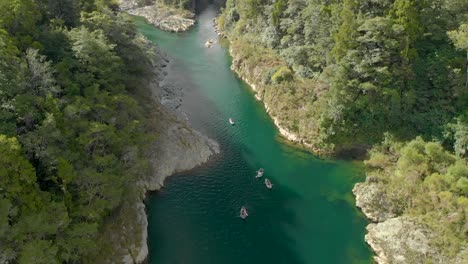 People-on-canoe-tour-paddle-beautiful-pristine-clear-blue-Pelorus-River,-New-Zealand---Aerial-Drone