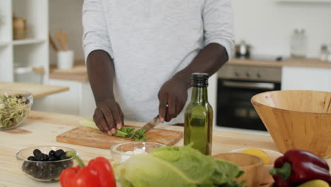 black man cooking vegetable salad at home