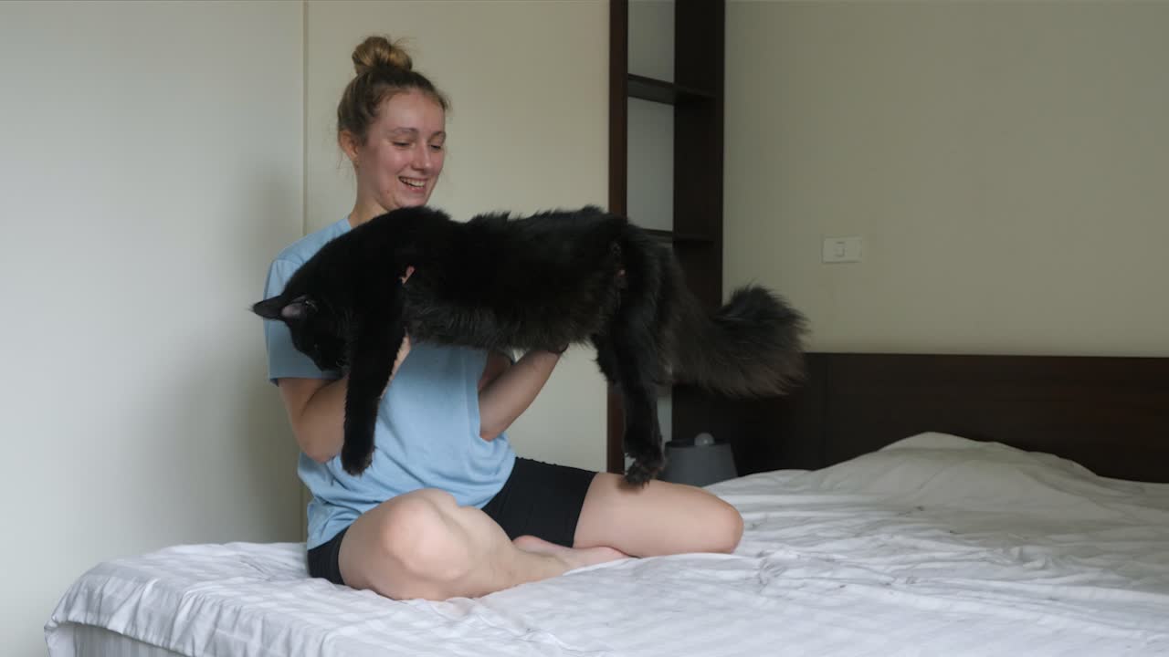 어린 암 ⁇ 이 높이 들고 그녀의 애완동물 검은 고양이, 느린 움직임을 뛰고 있습니다.