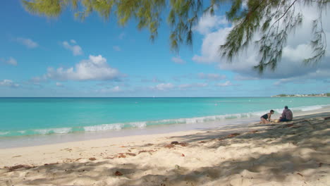 grand cayman, 7 mile beach, pan to two beachgoers