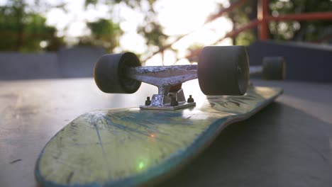 close-up shot of skateboard on the ground in sun beams