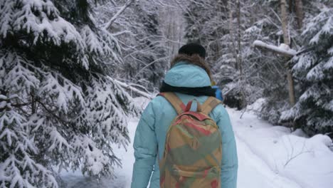 woman walking in a winter forest with a tourist backpack and people in a background in finland