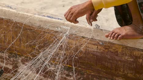 close-up of hands untangling a fishing net