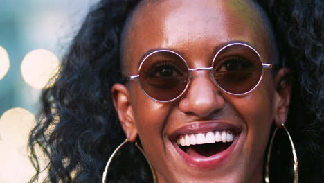 jovem negra usando óculos de sol redondos rindo, tiro na cabeça
