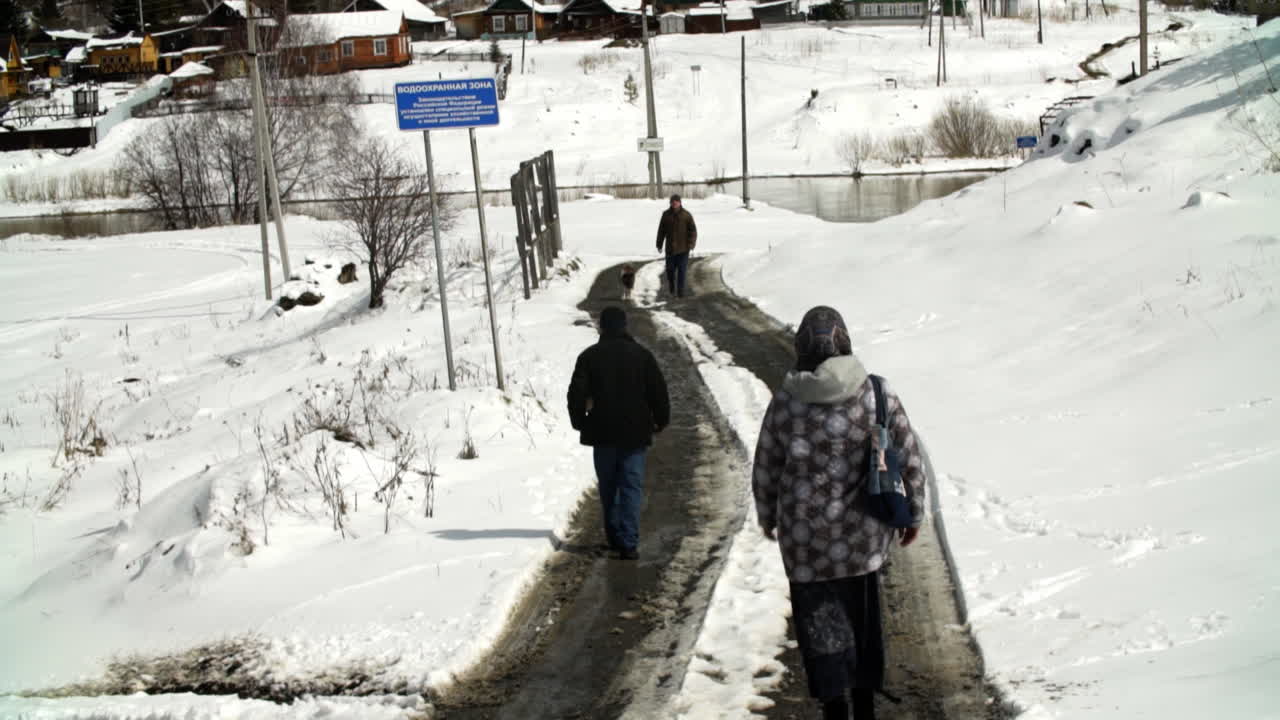 마을 의 강 근처 에 있는 눈 인 도로 를 고 있는 사람 들