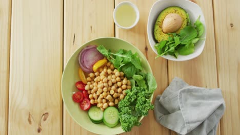 Video-of-bowls-of-fresh-salad-with-green-leaves-on-wooden-background