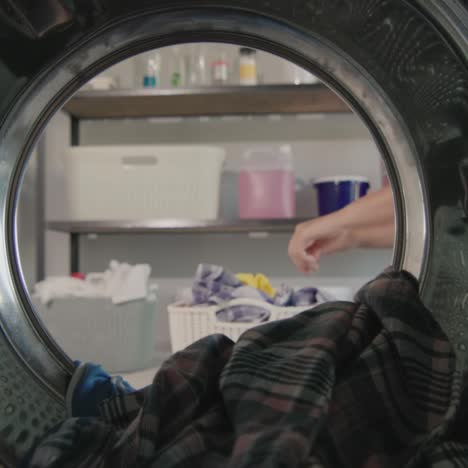 Woman-throws-dirty-laundry-into-the-washing-machine