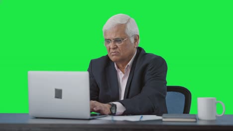 Confused-Serious-senior-Indian-manager-working-on-laptop-Green-screen