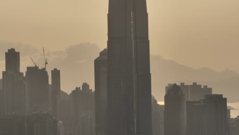 Silhouetten-Der-Hochmodernen-Wolkenkratzer-IFC-Und-Des-Zentrums-In-Einer-Parallaxendrohne,-Aufgenommen-Bei-Sonnenuntergang-In-Der-Skyline-Der-Stadt-Hongkong