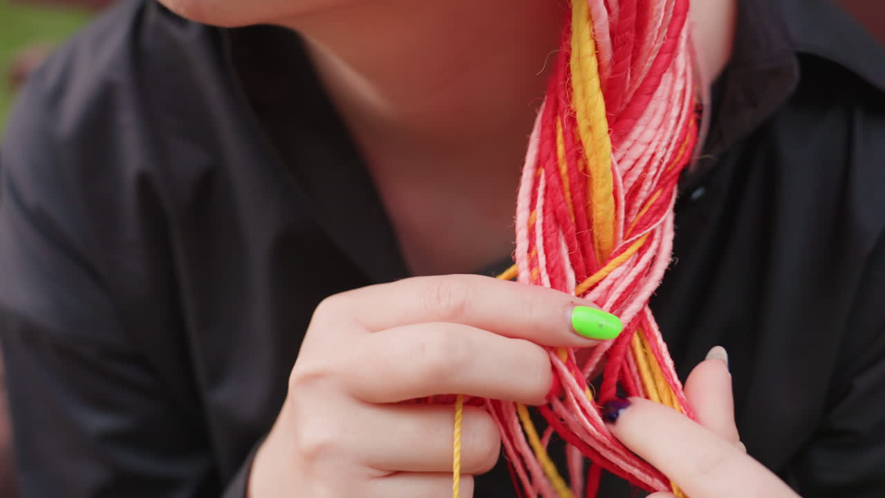얼굴 가까이에서 밝게 땋은 머리를 만지는 백인 여성, 조심스러운 손가락과 네온 네일이 머리카락을 가지고 놀고, 질감과 불안한 에너지가 느껴지는 섬세한 클로즈업, 벤치와 공원 분위기가 배경에 있어요.