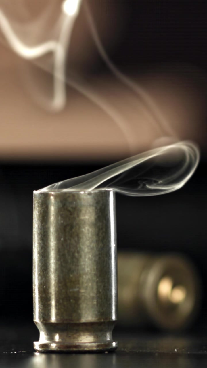 Primo piano di un bossolo fumante con fumo che sale
