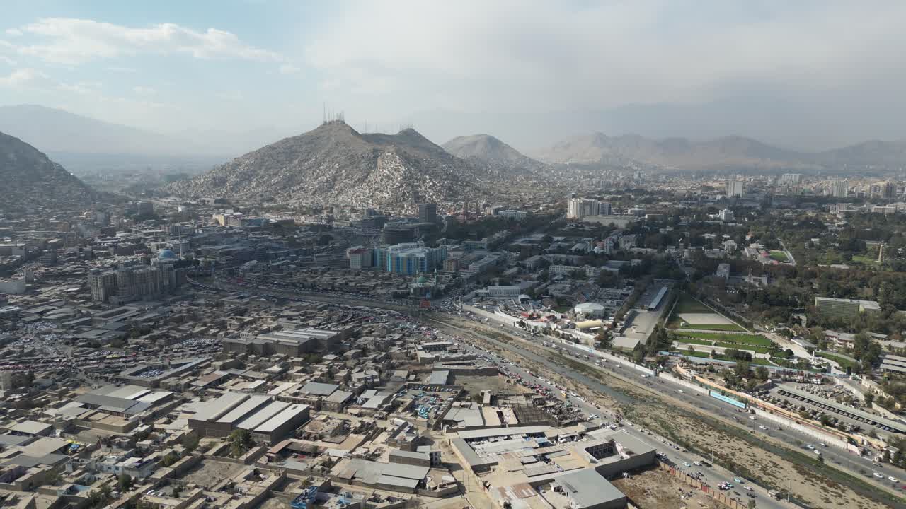 Aerial View of Kabul, Afghanistan. Road Traffic, Residential and Business Buildings Under Hills and Misty Sky