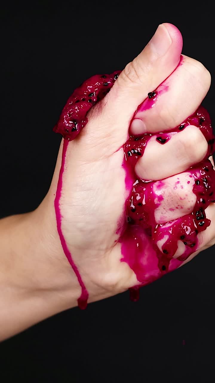 la mano apretando la fruta del dragón, el jugo goteando