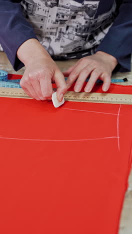 fashion design workshop. view of woman making pattern on red piece of material vertical video