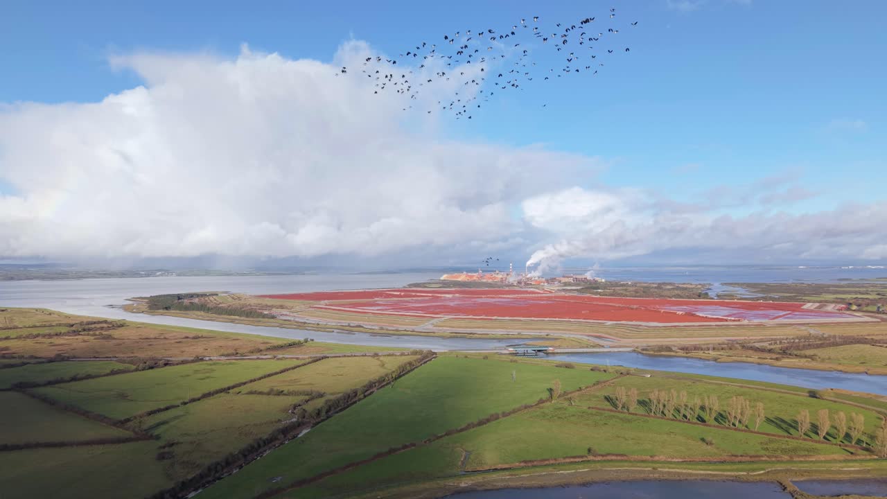 Green Fields Along The Robertstown River With Aughinish Red mud Limited Library In The Distance In Tooreenard, Limerick, Ireland. - aerial shot