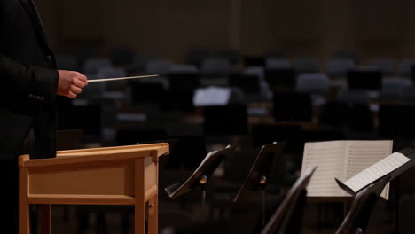 orchestra conductor with baton and music stands