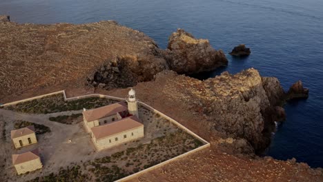 pull back aerial tilt down of punta nati lighthouse at golden hour