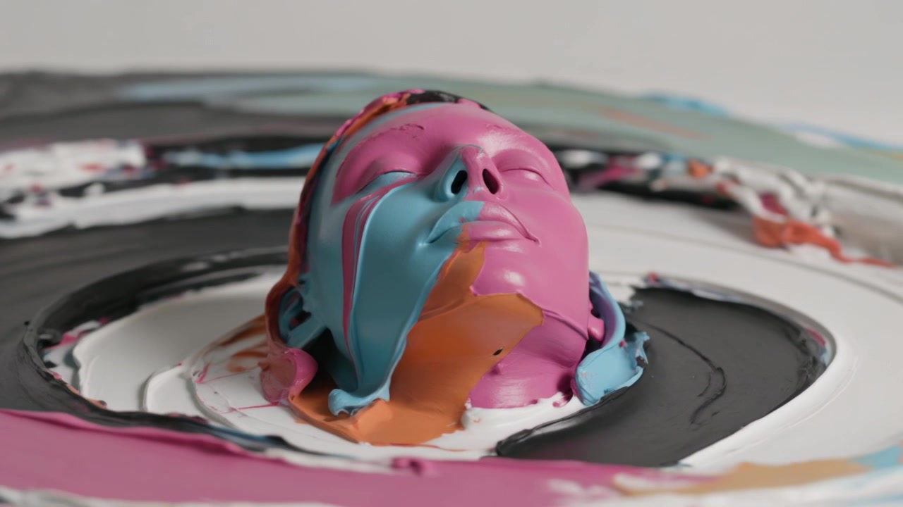 Pouring paints onto sculpted pink head, cyan, orange, black and white forming rings on turntable