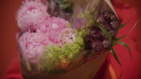 Person-in-red-coat-carrying-large-bouquet-of-flowers