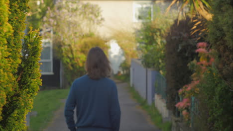 Man-strolls-away-from-focus-along-beautiful-neighborhood-path