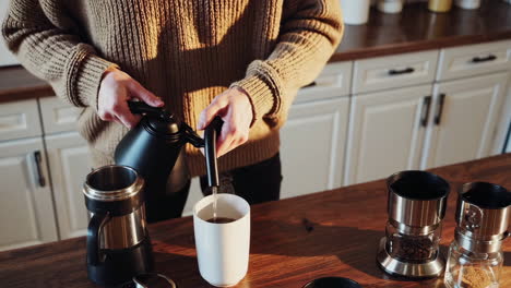 pouring coffee from a kettle into a mug in a kitchen
