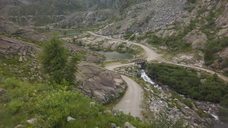 Scenic-landscape-of-the-road-and-a-small-lake-in-the-middle-of-the-green-and-rocky-mountains