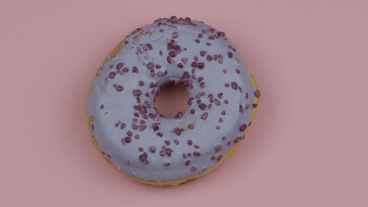 donut dulce girando sobre un fondo rosado. vista superior. donut sabroso y fresco rociado