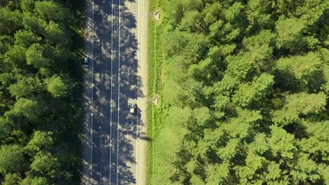 aerial flying over highway in the forest view vertically down on passing cars trucks