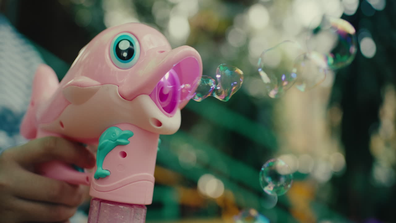 Pink dolphin-shaped bubble blower in hand, vibrant outdoor setting, playful and fun