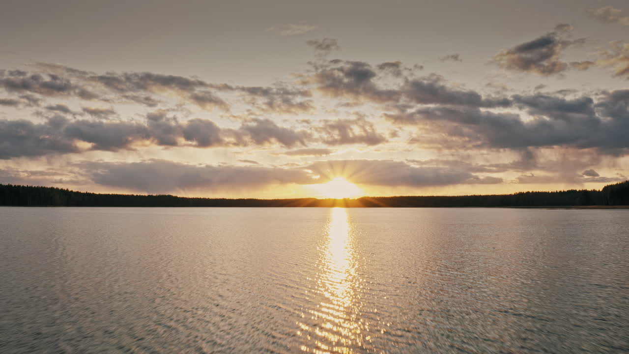Drone flight into sun over water. Sunset over water visible.
