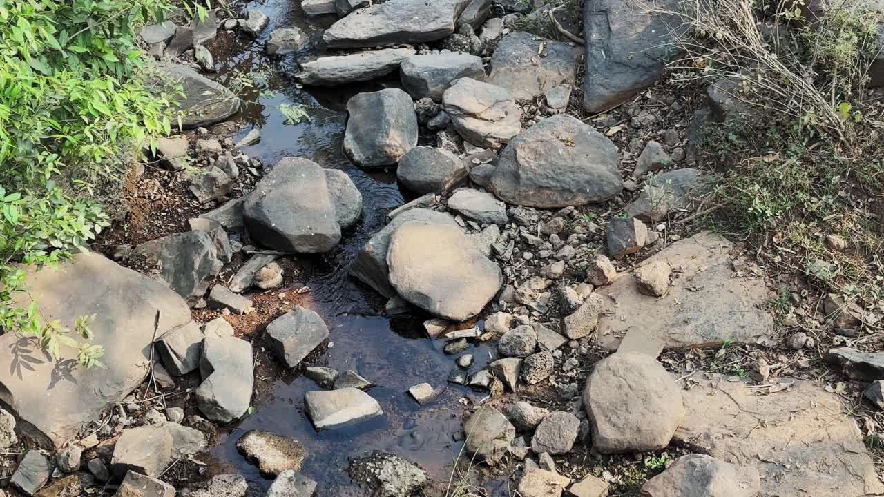 Inquadratura statica di acqua naturale limpida che scorre dolcemente tra rocce e sassi levigati, trasmettendo purezza, tranquillità, natura incontaminata ed ecosistemi d'acqua dolce