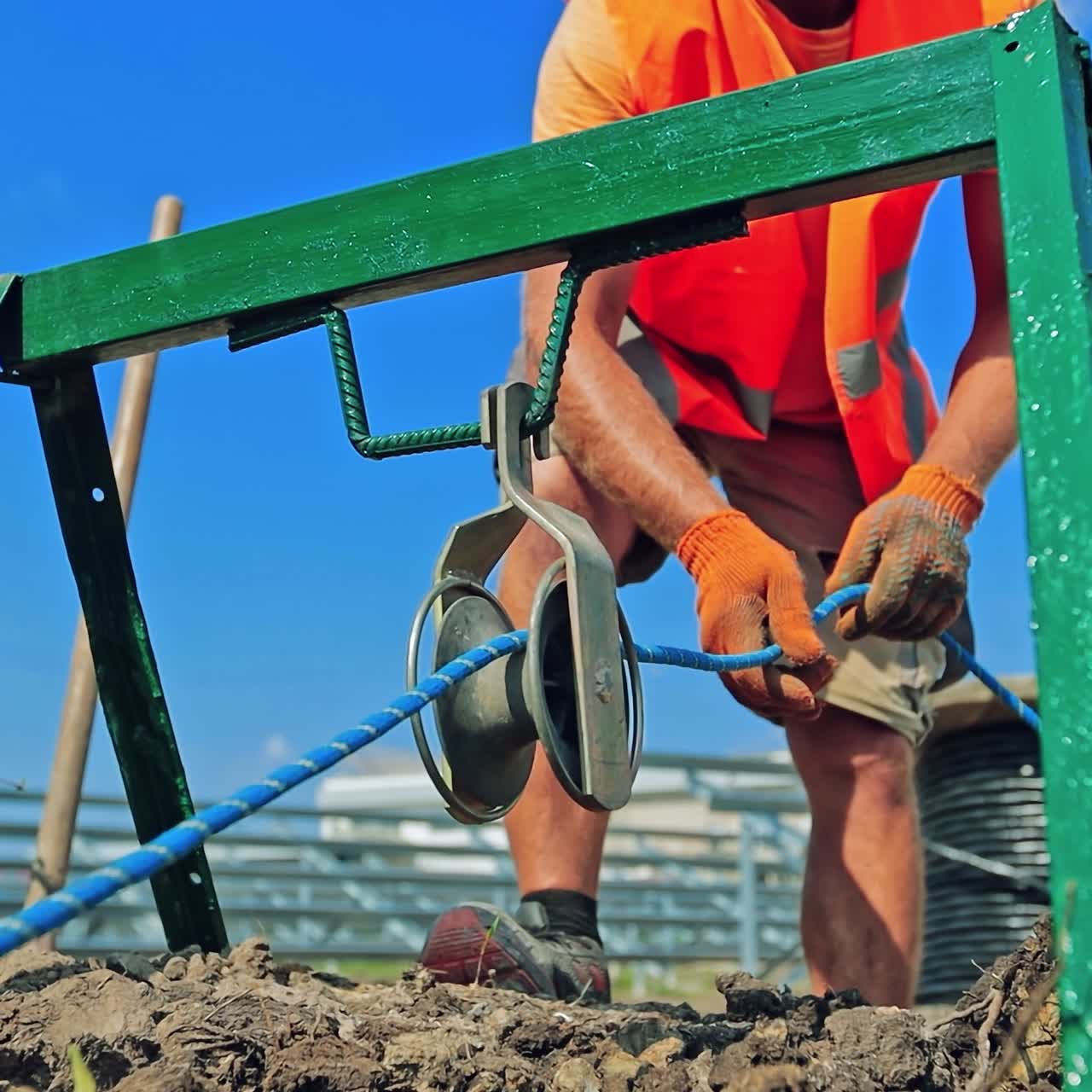 Engineering works. Technician works with building equipment outdoors. Construction area on the ground.